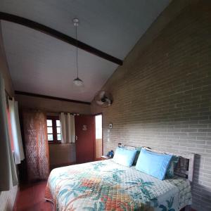 1 dormitorio con cama y pared de ladrillo en Espaço Puri, en Divino de São Lourenço