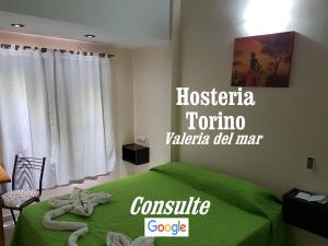 Un dormitorio con una cama verde con un cartel en la pared en Hosteria Torino en Valeria del Mar