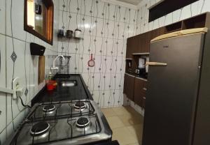 a kitchen with a stove and a refrigerator at Casa com piscina no centro de Maragogi pertinho da praia! in Maragogi