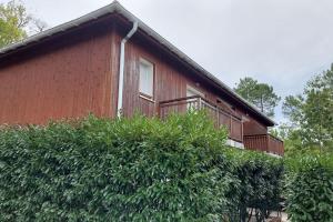 a red house with a balcony and some bushes at Appartement cosy in Biscarrosse