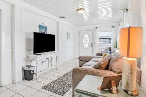 a living room with a couch and a tv at Vilano Beach Oasis Bungalow in St. Augustine