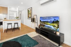 a living room with a flat screen tv on a wall at Morphett City Chic 1 bdrm Kitchen Wifi Pool in Adelaide