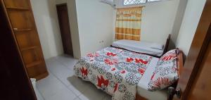a small bedroom with a bed with a red and white blanket at Departamentos extension Casa Paraíso in Manta