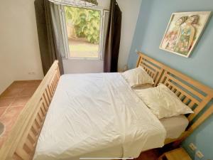 1 dormitorio con 1 cama con sábanas blancas y ventana en Marisol les pieds dans l eau en Le Gosier