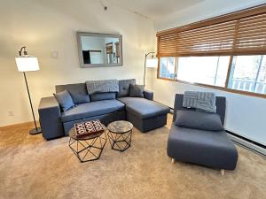 a living room with a blue couch and chairs at Sunday River Ski In Ski Out Mountain View Condo with Hot Tub Pool and Sauna! in Newry