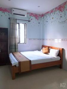 a bedroom with a bed with flowers on the wall at Ngan Giang Guesthouse in Phú Quốc