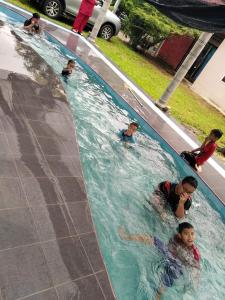 eine Gruppe von Personen, die in einem Schwimmbad schwimmen in der Unterkunft ISLAMIC HOMESTAY @ KUALA ROMPIN , PAHANG . in Kuala Rompin