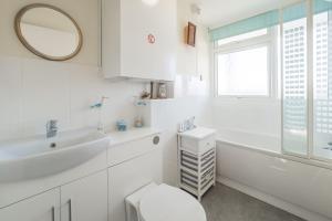 a white bathroom with a sink and a tub and a toilet at 18 Undercliffe in Felixstowe