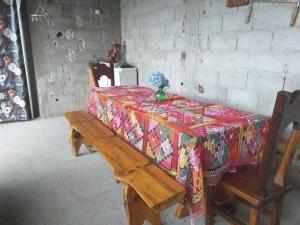 einen Tisch mit einem geblümten Tischtuch und einer Holzbank in der Unterkunft Cantinho da Serra in Santo Antônio do Pinhal