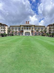 a large building with a large green field in front of it at The Bromeliad at Turtle Cove Villas in Kiawah Island