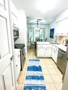 a kitchen with white cabinets and a blue rug on the floor at The Bromeliad at Turtle Cove Villas in Kiawah Island