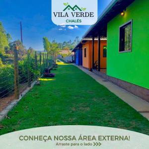 a green yard next to a building with a fence at Vila Verde Chalés-Serro in Sêrro