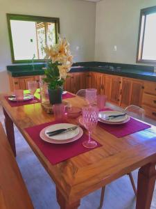 a wooden table with plates and wine glasses on it at Vila Verde Chalés-Serro in Sêrro
