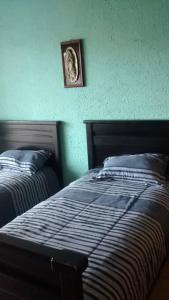 een slaapkamer met 2 bedden en een foto aan de muur bij Habitaciones disponibles en los nogales Pátzcuaro in Pátzcuaro