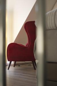 a red chair sitting next to a bed at Hommage Appartements in Waren