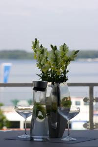 Eine Vase mit einer Pflanze neben zwei Gläsern. in der Unterkunft Hommage Appartements in Waren (Müritz)