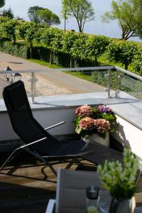 a black chair sitting on a balcony with flowers at Hommage Appartements in Waren