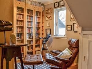 a living room with a chair and book shelves at 1 The Courtyard in Kinneff