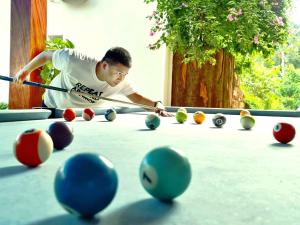 a man playing a game of pool on a pool table at Trang An Resort in Ninh Binh