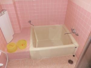 uma casa de banho cor-de-rosa com uma banheira e um lavatório. em ペンションレークサイド em Otsu