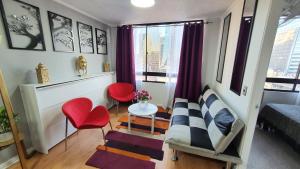a small room with a couch and red chairs at Cómodo departamento en bellas artes con vista privilegiada in Santiago