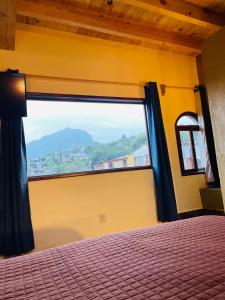 1 dormitorio con ventana grande con vistas a la montaña en Ma Petite Maison, en Tepoztlán