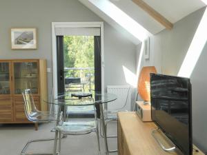 uma sala de jantar com uma mesa de vidro e uma televisão em Priory Barn em Freshwater