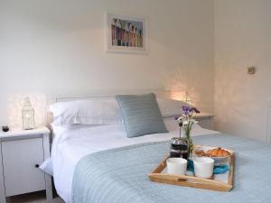 a bed with a tray of food and flowers on it at Priory Barn in Freshwater