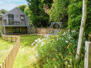 a garden with a house and a swing at Priory Barn in Freshwater