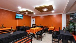 a restaurant with tables and chairs and a tv on the wall at Hotel Miraflores in Ibarra
