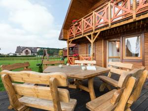 una terraza de madera con mesa de madera y bancos en Big Cottages in Rewal en Rewal