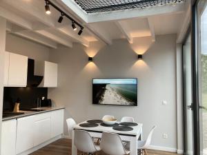 a kitchen with a white table and a tv on the wall at Holiday house with swimming pool for 7 people in Swinoujscie in Świnoujście