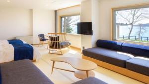 1 dormitorio con sofá, cama y TV en Kyukamura Kesennuma-Ohshima en Kesennuma