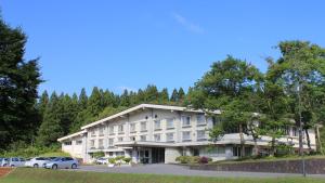 een groot hotel met auto's geparkeerd op een parkeerplaats bij Kyukamura Shonai-Haguro in Tsuruoka