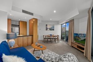 a living room with a blue couch and a table at Exclusive Stays - Gallery Tower in Melbourne