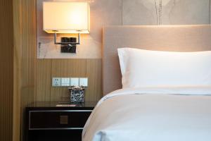 um quarto com uma cama e um candeeiro sobre uma mesa em The Yun Hotel Hankou em Wuhan