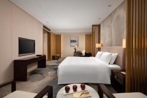 a hotel room with a large bed and a television at The Yun Hotel Hankou in Wuhan