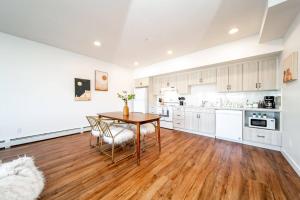 a kitchen with white cabinets and a wooden table and chairs at Hot Arabaian NightsCornerPNHSEkingWifiU/G in Edmonton