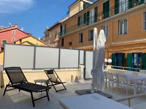 einen großen Bildschirm auf einem Balkon mit Stühlen und einem Sonnenschirm in der Unterkunft Villetta Gramsci, Alassio in Alassio