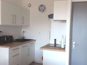 a kitchen with white cabinets and a clock on the wall at Appartement Villard-de-Lans, 3 pièces, 6 personnes - FR-1-689-21 in Villard-de-Lans