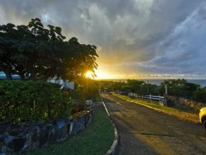an empty road with a sunset in the background at Alamanda studio à 2 mn de la plage in Friar's Bay +5 photos