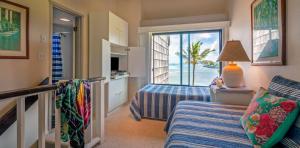 a bedroom with two beds and a balcony with a view of the ocean at Sealodge E6 in Princeville