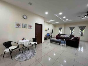 ein Wohnzimmer mit einer Couch und einem Tisch und Stühlen in der Unterkunft Titihouse Spacious Semi-D for 10 pax near Iconcity Autocity in Bukit Mertajam