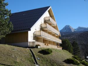 un edificio en una colina con una montaña en el fondo en Studio Corrençon-en-Vercors, 1 pièce, 5 personnes - FR-1-689-62, en Corrençon-en-Vercors