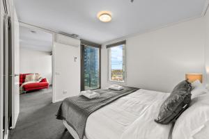 a white bedroom with a bed and a large window at Exclusive Stays - The Summit in Melbourne