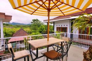 AirsatangMedewi Hady Surf Camp的阳台配有桌椅和遮阳伞