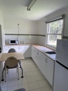 una cucina con armadi bianchi, tavolo e finestra di Sinclairs Country Retreat a Conjola