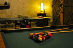 una mesa de billar con bolas de taco y una mesa en La Grande Maison, en Pas-de-Jeu