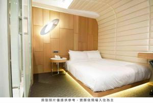 um quarto com uma cama branca e uma pequena mesa em Royal Hotel Group- Central Park Branch em Kaohsiung