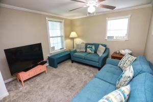 a living room with a blue couch and a flat screen tv at Quick & Intimate Beach Getaway in Galveston